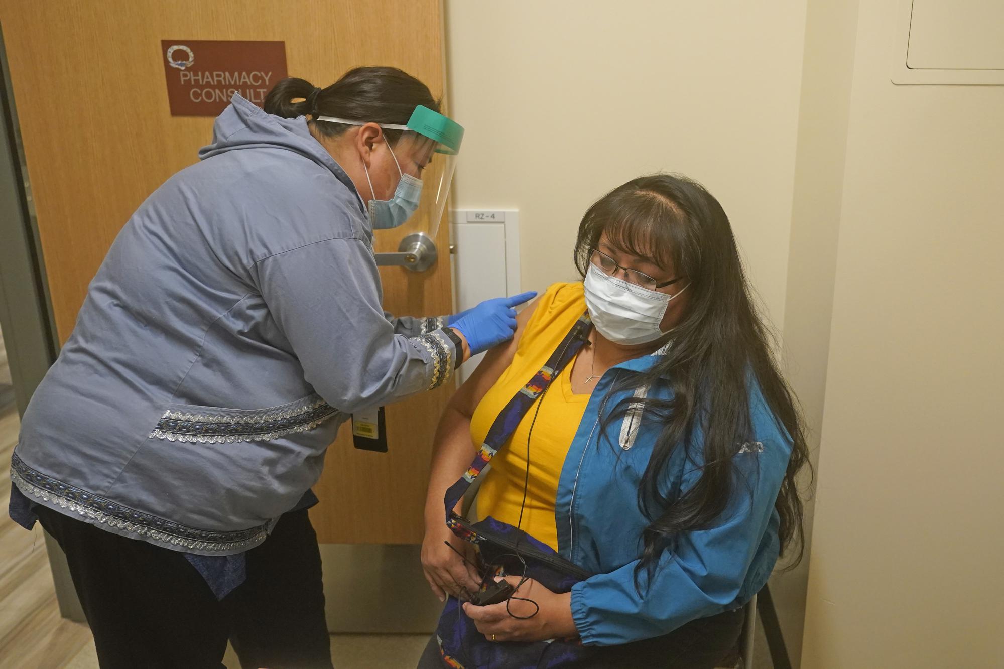 Samantha Ervin, left, a pharmacist at the Upper Tanana Health Center, administers the second COVID-19 vaccine shot to Maggie Roach Thursday, Sept. 23, 2021, in Tok, Alaska. Roach was at first hesitant to get the vaccine but changed her mind after contracting COVID-19 and nearly dying from it last summer. She now encourages other to consider getting vaccinated if they haven't. That's what she and her husband did. (AP Photo/Rick Bowmer)