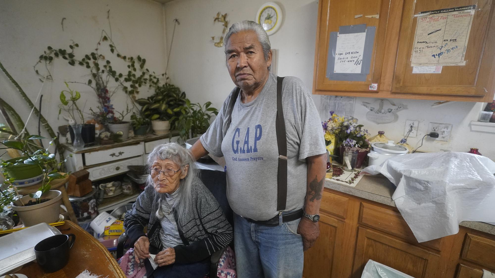 Arthur John, 82, a retired trapper, and his wife of 62 years, 99-year-old Isabel pose for a photograph at their home Thursday, Sept. 23, 2021, in Tanacross, Alaska. Arthur John spent nearly 30 days at in the hospital with COVID, dropping about 40 pounds during his stay. "It makes me weak and can't work like before," the village elder said. "There's so much it took off me and I just wish for working." (AP Photo/Rick Bowmer)