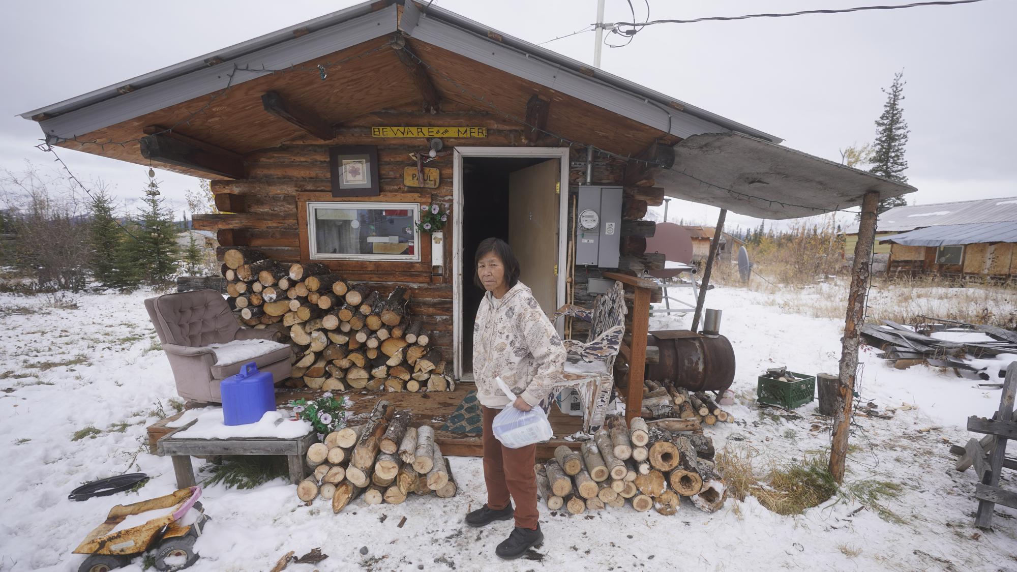 Marilyn Paul stands in front of her home Thursday, Sept. 23, 2021, in Tanacross, Alaska. Alaska is experiencing one of the sharpest rises in COVID-19 cases in the country, coupled with a limited statewide healthcare system that is almost entirely reliant on Anchorage hospitals. (AP Photo/Rick Bowmer)